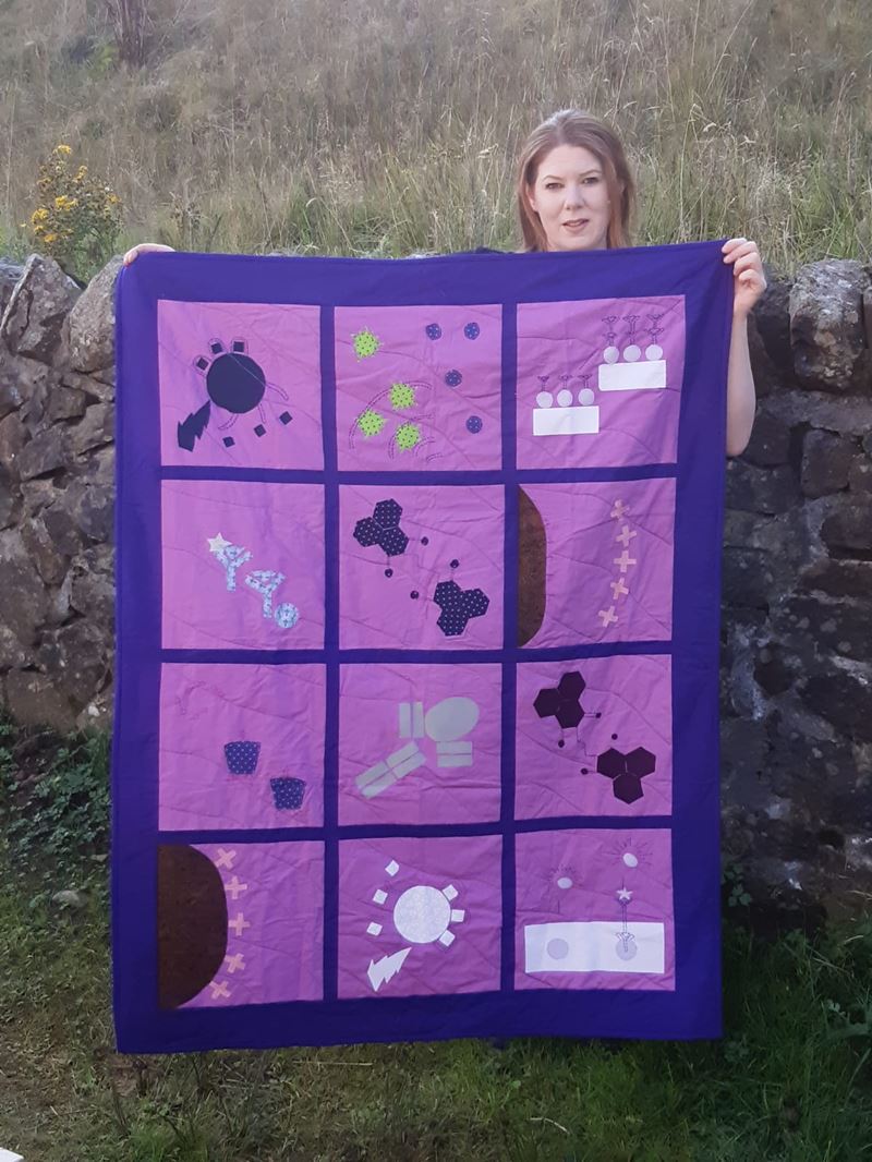 Clare Hoskins holding up a purple quilt