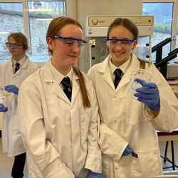 Two female students wearing safety goggles take part in an experiment