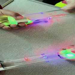 Two pairs of hands on a glass tube with lights at each end