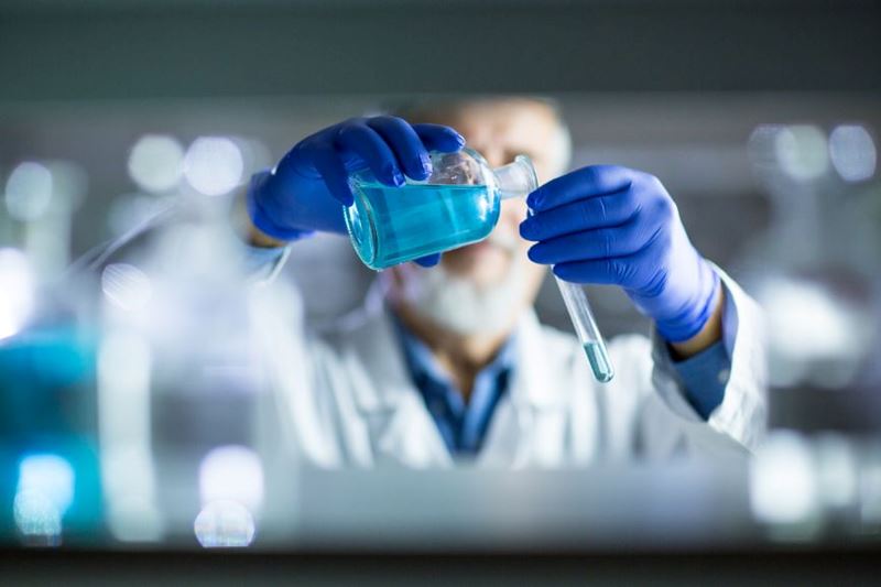 A scientist pours liquid into a test tube