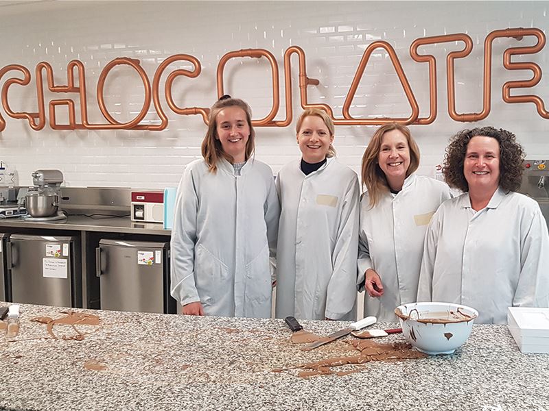 Image shows a group of people chocolate tempering with Kate Rose, apprentice food technologist at Mondelez, alongside Dr Stacey Lockyer, Elaine Hindal and Frances Meek from the British Nutrition Foundation.