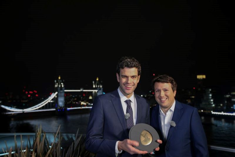 Notpla co-founders Rodrigo Garcia Gonzalez and Pierre Paslier stand on a hotel balcony with the Earthshot Prize trophy, with London's Tower Bridge in the background