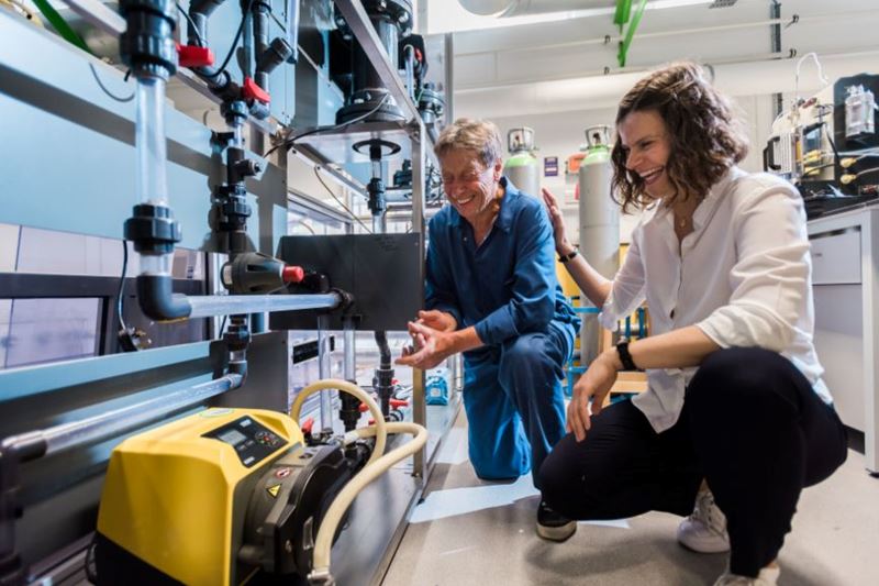 Dr Ola Hekselman laughs in the Solveteq laboratory while working in front of a large piece of machinery with a colleague