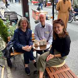 Helen Pain, Antony Galea and Sara Bosshart smile and sit together on a bench in Japan