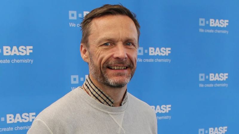 A portrait picture of Tony Heslop in front of a sky blue background with BASF logos all over.