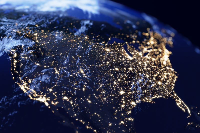 A photograph of North America from space with the continent in darkness apart from lights shining in cities across the whole area