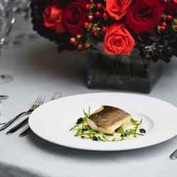 fish fillet on plate next to flowers