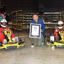 Professor Saiful Islam holding the official GUINNESS WORLD RECORDS™ certificate alongside two go-karts used in the race
