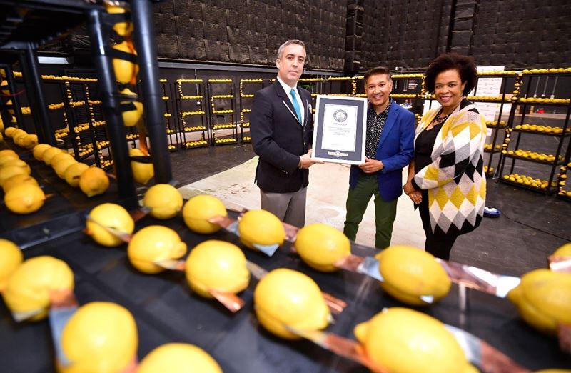 Profssor Saiful Islam holding the world record certificate with lemons on racks in the foreground